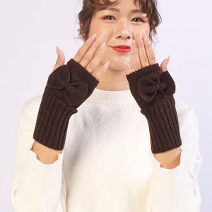 Detail view of dark brown knitted fingerless gloves with bow accent on a model