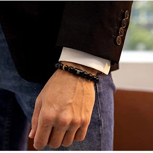 Detailed view of black beaded bracelet with a gold letter B charm on a male wrist