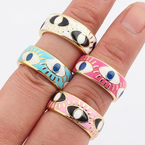 Macro view of colorful enamel evil eye rings in white, blue, and pink on a person's hand
