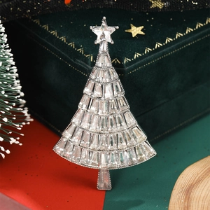 Macro shot of silver Christmas tree brooch with rhinestones on green velvet