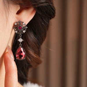 Détail des boucles d'oreilles fleurs vintage avec pierres rouges en goutte d'eau