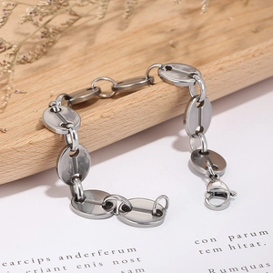 Detailed view of silver coffee bean link bracelet with lobster clasp on a wooden tray