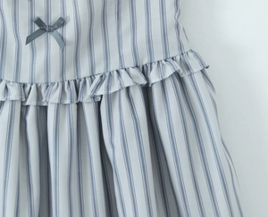Detailed close-up of blue and white striped dress with waist ruffles and bow decoration