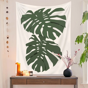 Detail eines Monstera-Wandteppichs über einem Holzschrank in einem gemütlichen Zimmer