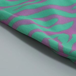Detail of sheer mesh fabric featuring a vibrant green and purple wavy zebra print pattern