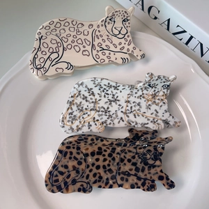 Pinze per capelli in acetato a forma di leopardo in tre colori su un piatto bianco