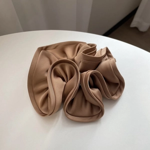 French style satin champagne scrunchie with large ruffle texture on white surface