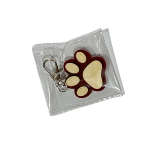 Close-up of wooden paw print keychain with silver metal carabiner in clear packaging
