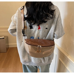 Rear view of model wearing a beige and brown crescent crossbody bag with double zippers