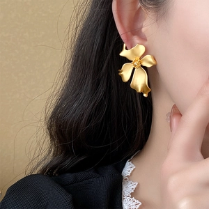 Close-up of matte golden flower earring worn by a model in French vintage style