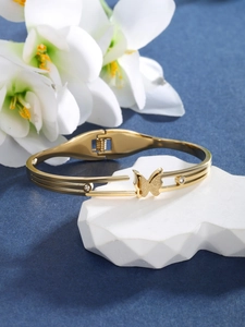 Detailed macro of gold butterfly bangle with crystals on a geometric stone base