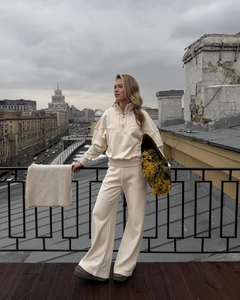 Detail of a beige half-zip sweatshirt and high-waist wide-leg pants on a model
