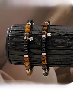 Close-up of tiger eye and obsidian beaded bracelets on a black textured jewelry display