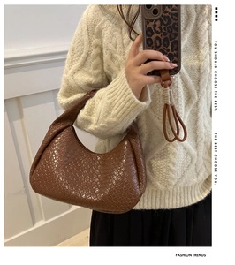 Brown woven leather underarm bag shown worn by a model in a casual lifestyle mirror selfie