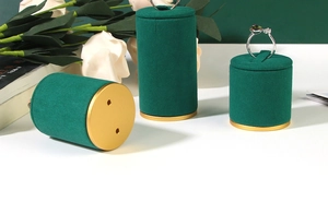 Detailed view of three dark green velvet ring display stands with gold metal bases