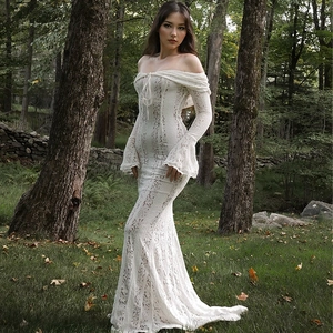 Dettaglio dell'abito lungo in pizzo bianco con eleganti maniche a tromba e orlo a sirena