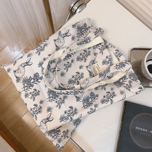 Detail of canvas tote bag showing artistic rabbit prints and sewn brand label