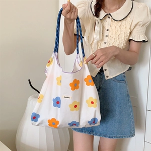 Detail of floral tote bag with blue and orange flower patterns and woven rope handles