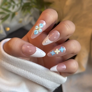Macro detail of almond press-on nails with 3D blue flowers and 3D clear water droplets