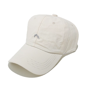 Detailed view of the embroidered blue letter M on a beige breathable baseball cap
