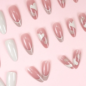 Pastel pink almond press-on nails with white heart patterns and French tips design