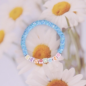 Detail of Bohemian beaded bracelet with light blue clay discs and celestial symbols