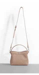 Detail of brown woven textured crossbody bag with metal twist lock and long shoulder strap