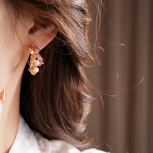 Close-up of gold plated C-shaped earrings with strawberry quartz and pearls