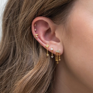 Close-up of golden earring set with star and moon charms and clear zircon inlay