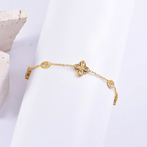 Macro shot of gold stainless steel bracelet with clover and oval zircon charms