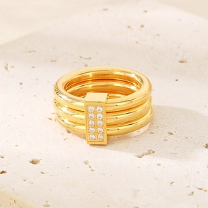 Macro shot of gold-plated titanium ring with inlaid zircon stones on beige stone surface