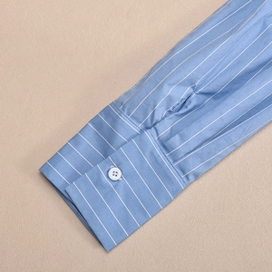 Detailed macro view of blue and white striped shirt cuff with white resin button