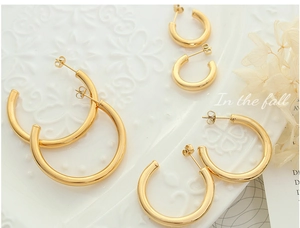 Three sizes of 18K gold plated C-shaped hoop earrings displayed on a white textured plate