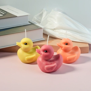 Detailed view of three cute duck shaped scented candles in pink, yellow and orange tones