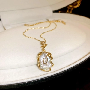Gros plan du pendentif en perle baroque avec motif feuille dorée et détails en zircon