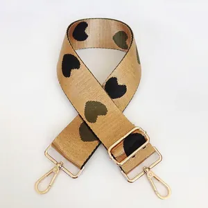 Adjustable khaki nylon bag strap with green heart patterns and gold metal hooks