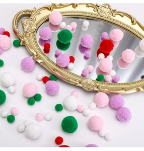 Close-up of colorful mixed-size fluffy pom-poms with an elegant gold oval mirror background