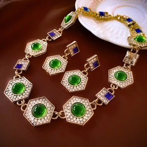 Detailed macro shot of vintage gold necklace and earrings with green and blue gemstones