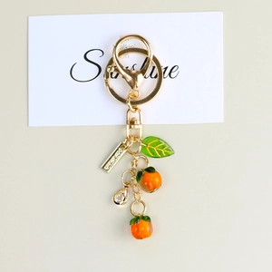 Close-up of cute persimmon keychain with orange fruit charms and a green leaf charm