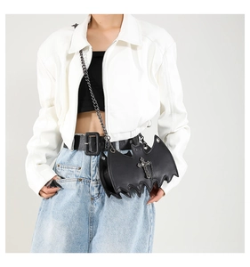 Close-up of bat-shaped leather bag featuring a silver cross and metallic chain detail