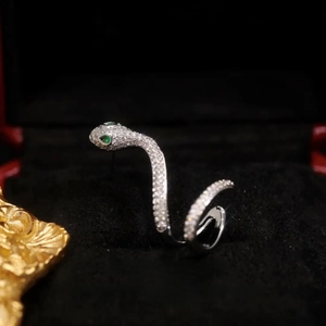 Vue macro d'un earcuff serpent en argent avec zircone et yeux en pierres vertes en boîte