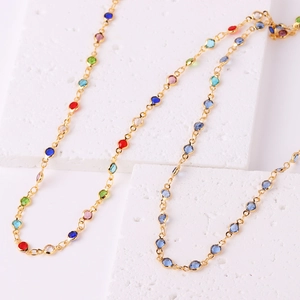 Detail of gold-plated chains with colorful cubic zirconia on white textured stones