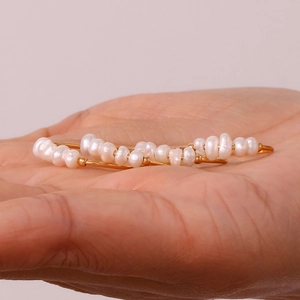 Close-up of gold stainless steel hoop earrings with delicate white freshwater pearls