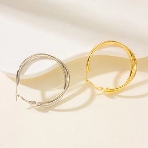 Minimalist gold and silver layered hoop earrings with triple-ring design on white stand