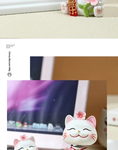 Detail showing white resin lucky cat figurine holding a scroll with floral accents