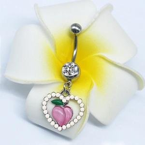 Detail of silver belly ring with pearl-framed peach heart charm on a frangipani flower