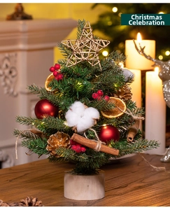 Detailed view of mini Christmas tree with red balls, pine cones and warm LED lights