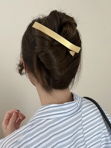Gros plan d'une barrette en métal doré brossé élégante sur un chignon de cheveux foncés