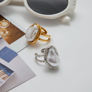 Golden and silver baroque pearl rings with adjustable double-line band on magazine background