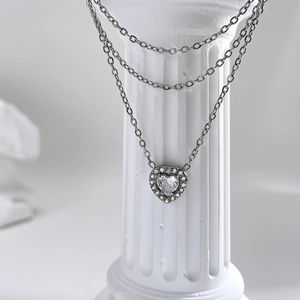 Elegant double-layer silver heart necklace with crystal diamonds on a Roman column